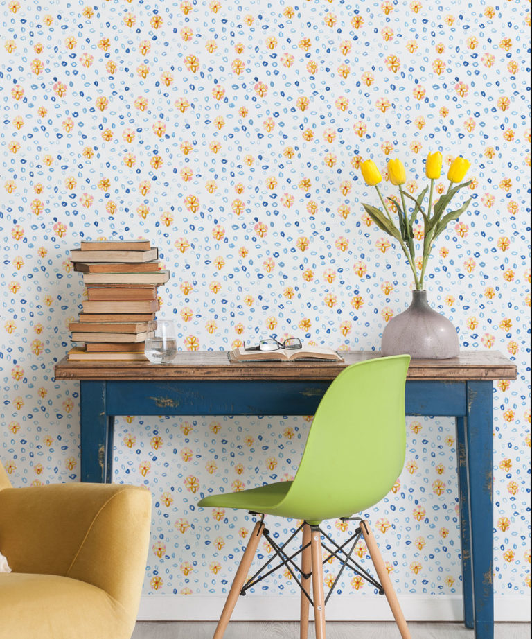 Al Hadiqa Wallpaper • Dainty Floral Design • Desk with books stacked on the left and a lime green chair in front with yellow tulips in a vase on the right side of the desk. • Milton & King Uk